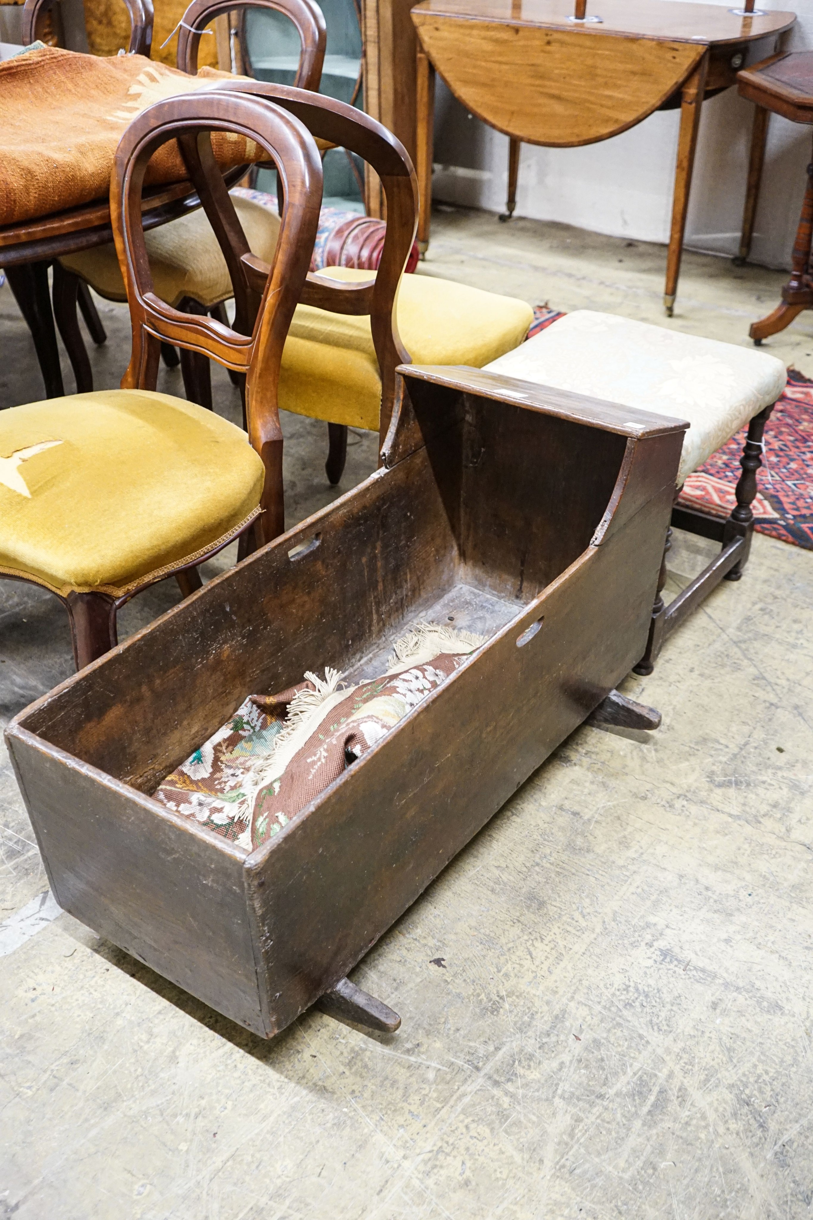 An 18th century elm cradle, length 97cm, depth 95cm, height 54cm together with a turned oak stool with padded seat, width 43cm